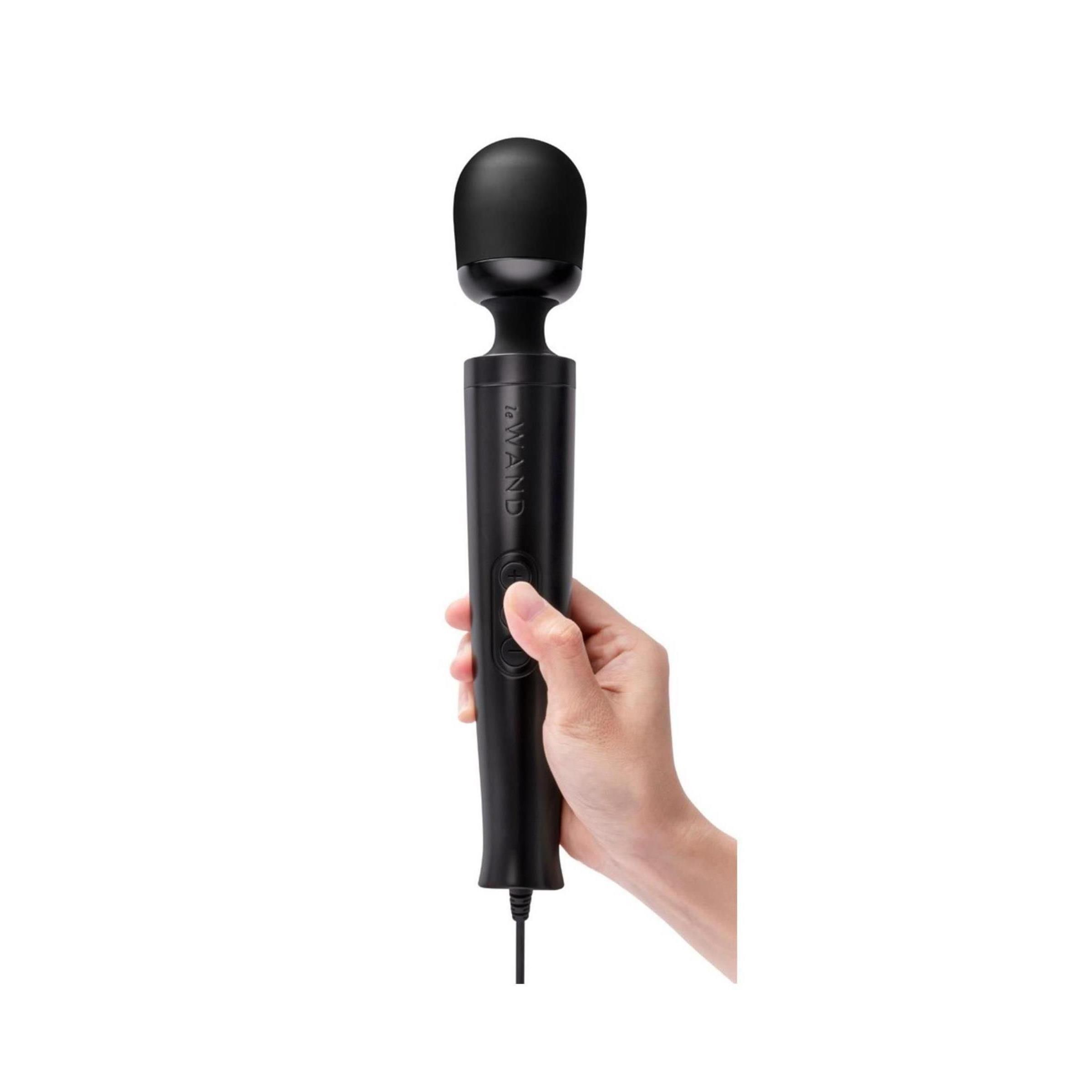 Hand die een zwarte massagestaaf "Diecast Plug-In" met kabel vasthoudt.