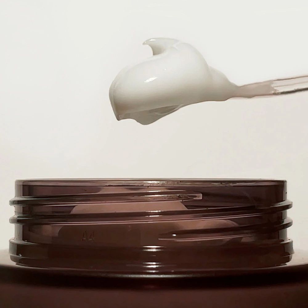 Crème op een lepel. Crème is wit. De achtergrond is wit.