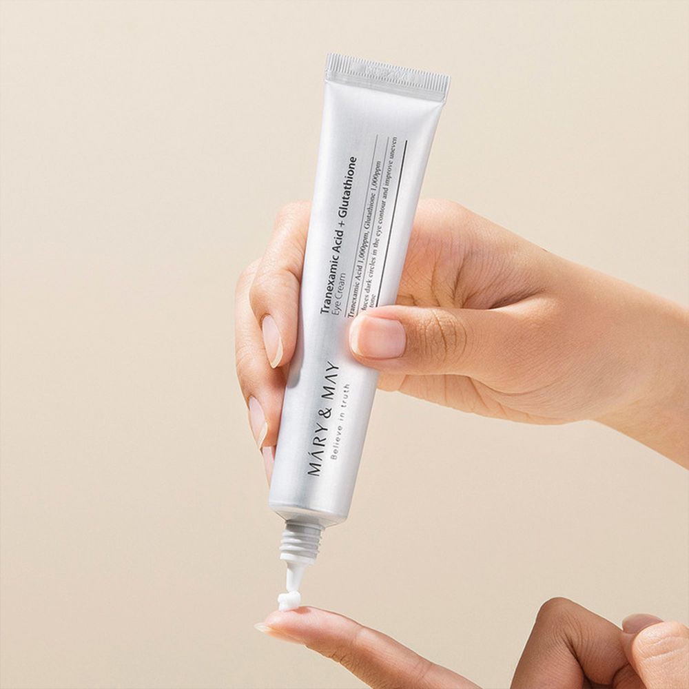 Hand houdt tube vast. Crème wordt op vinger aangebracht. MARY & MAY logo en producttekst zichtbaar.