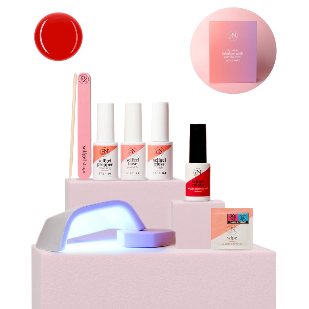 Kit PN Selfcare. Vernis rouge, lime à ongles, 3 flacons, lampe LED, lingettes. Sur socle rose. Emballage en arrière-plan.