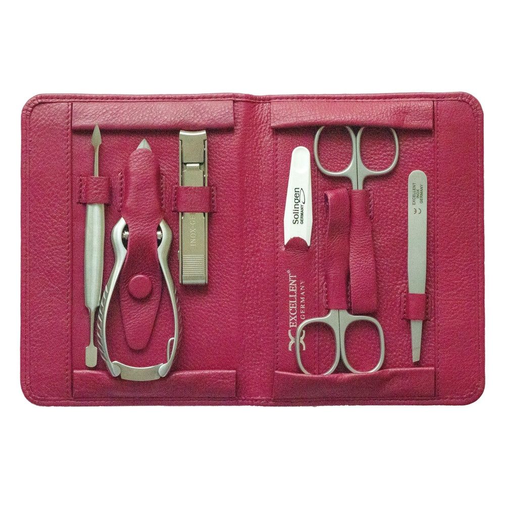 Een geopend manicure-etui van roze leer met zeven instrumenten, waaronder een nagelknipper, schaar en pincet.
