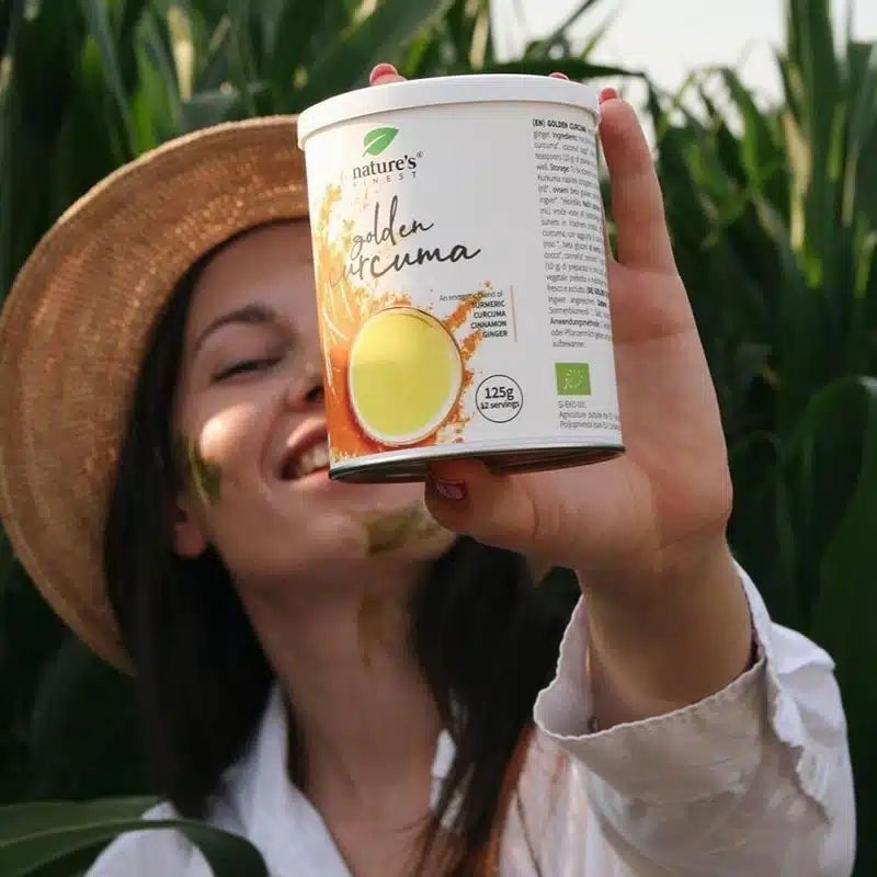 Vrouw met strooien hoed houdt een blikje Nature's Finest Golden Curcuma Latte vast.