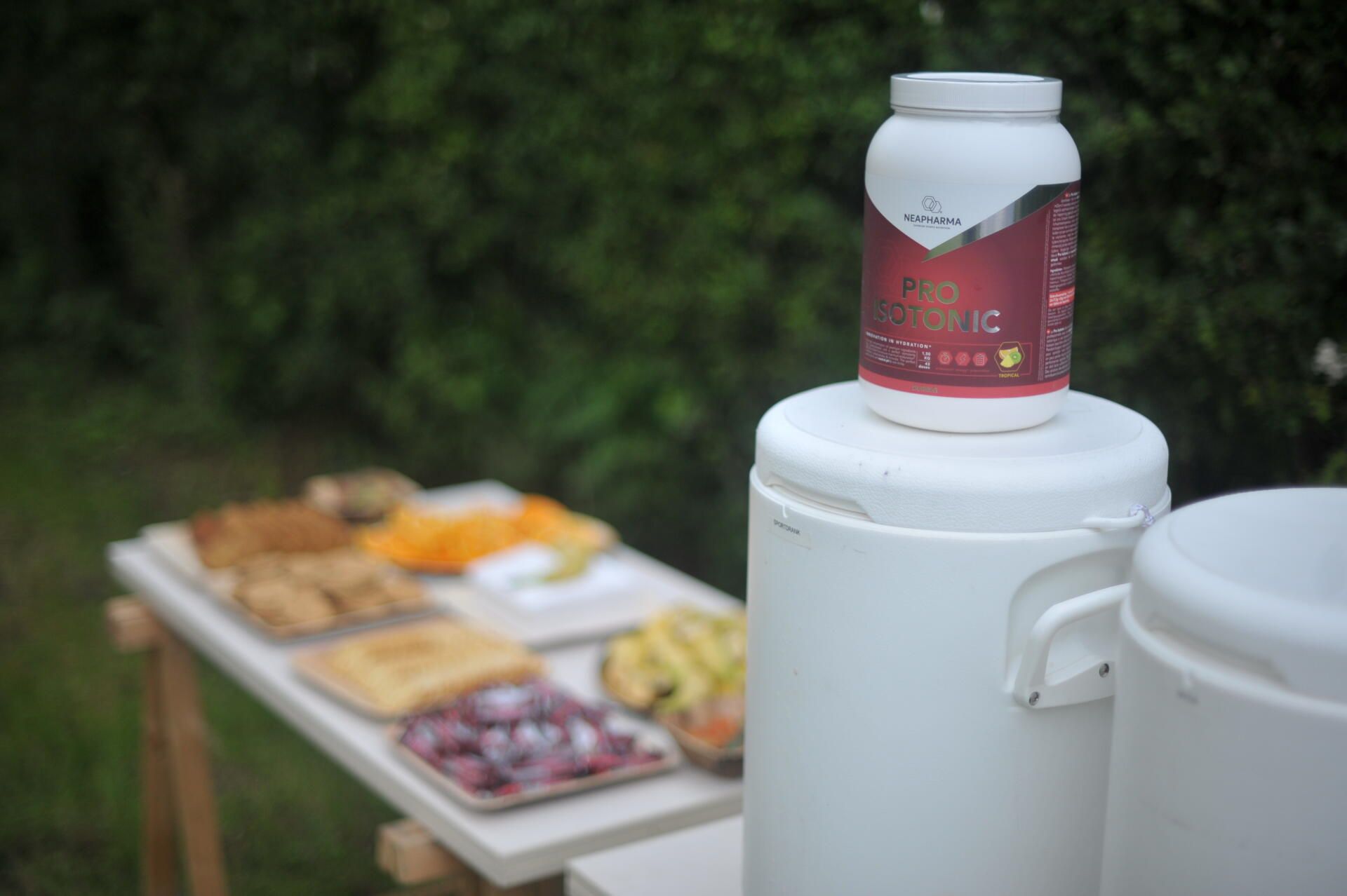 Récipient blanc avec étiquette rouge sur un conteneur blanc. En arrière-plan : nourriture sur une table en plein air.