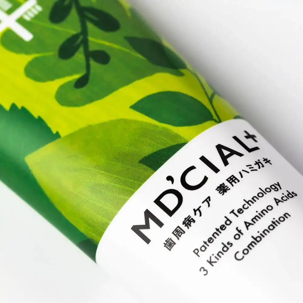 Gros plan sur le tube de dentifrice MD'CIAL+. Design vert, inscription. Inscription: Patented Technology, 3 Kinds of Amino Acids.