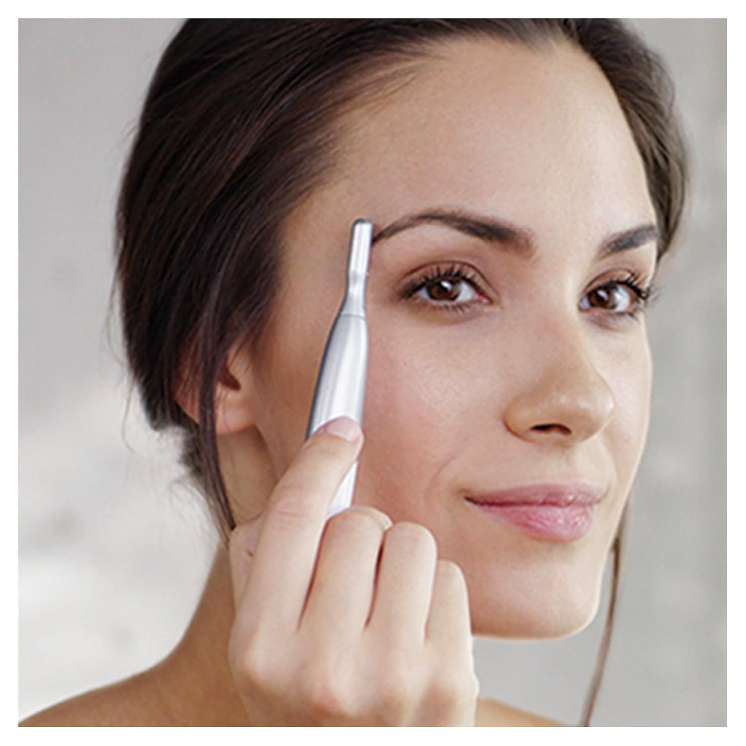 Une femme utilise un taille-sourcils argenté.