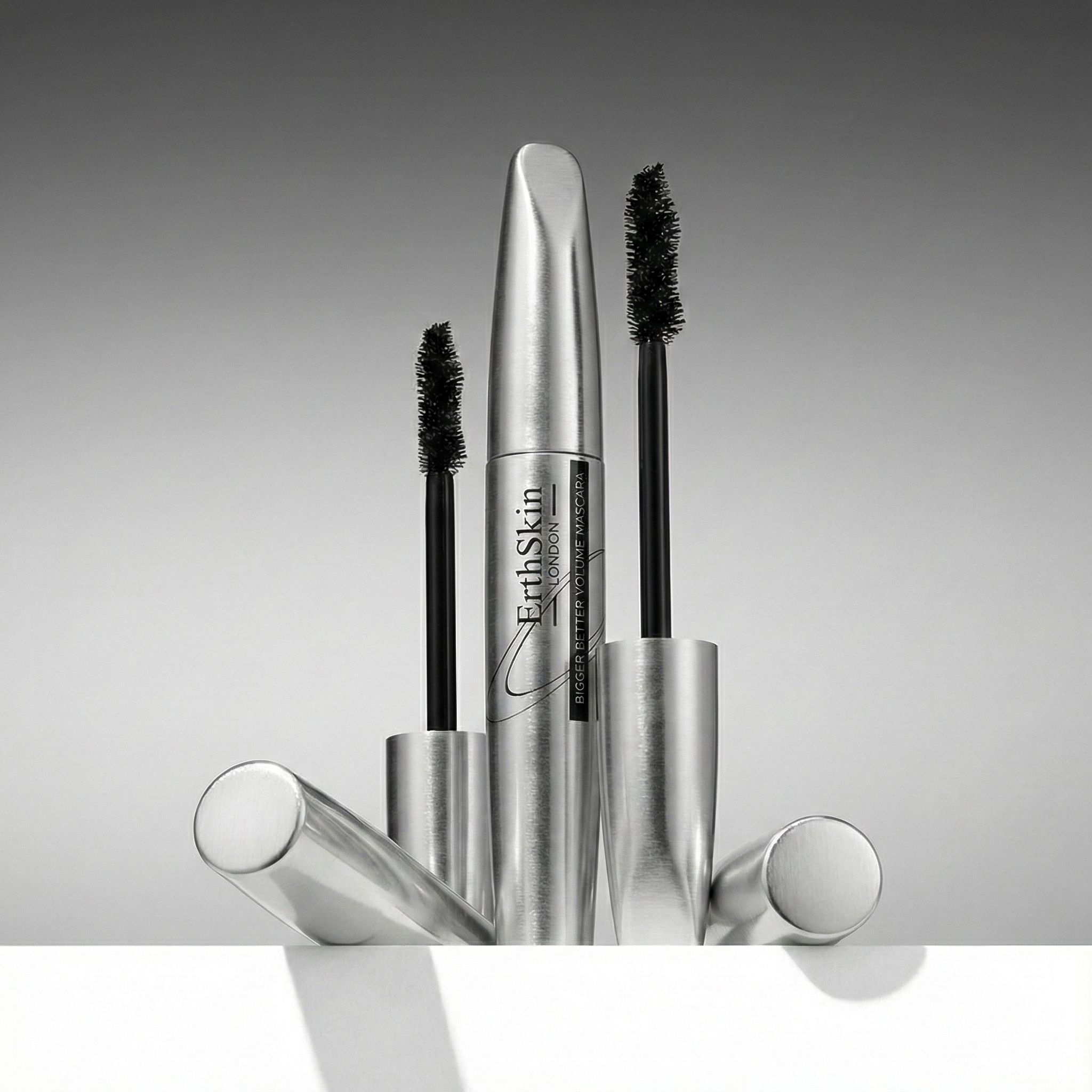 Trois tubes de mascara argentés et applicateurs à brosse noire.