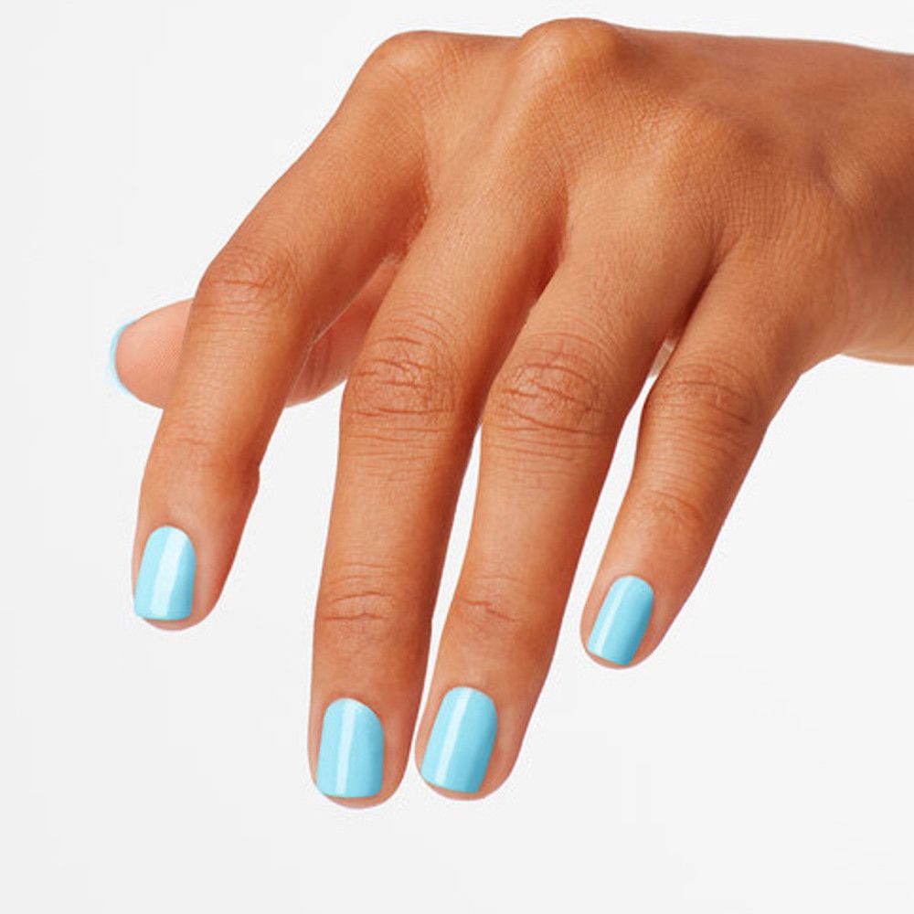 Main avec ongles peints en bleu clair. Les ongles sont courts et uniformément vernis.