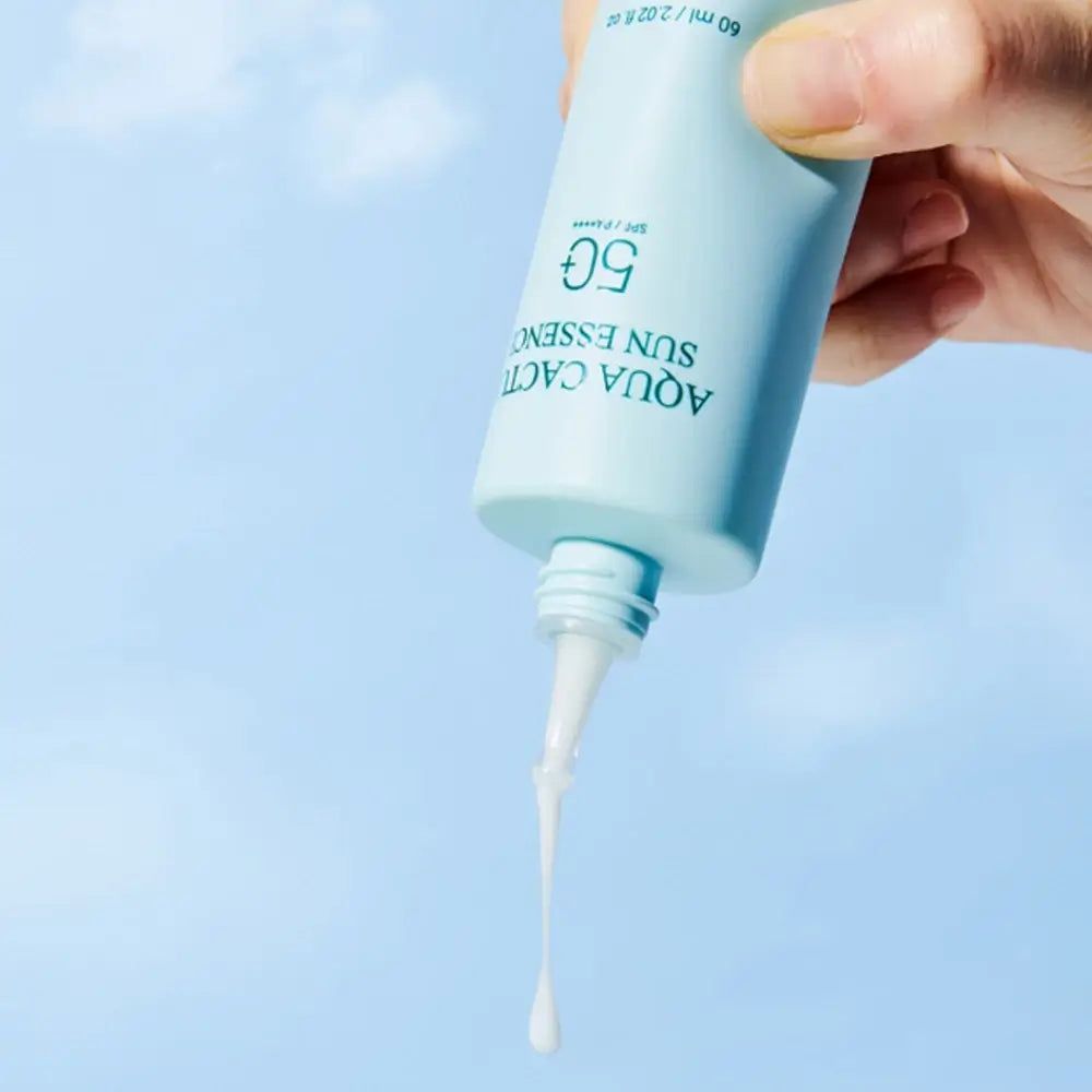Lichtgroene fles met witte applicator. Opschrift: Aqua Cactus Sun Essence 50. Product wordt uit de fles geperst.