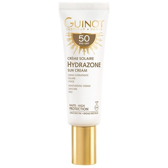 Tube de crème solaire blanche, bouchon doré. Inscriptions: Guinot, Hydrazone, SPF 50. Haute protection. Visage.