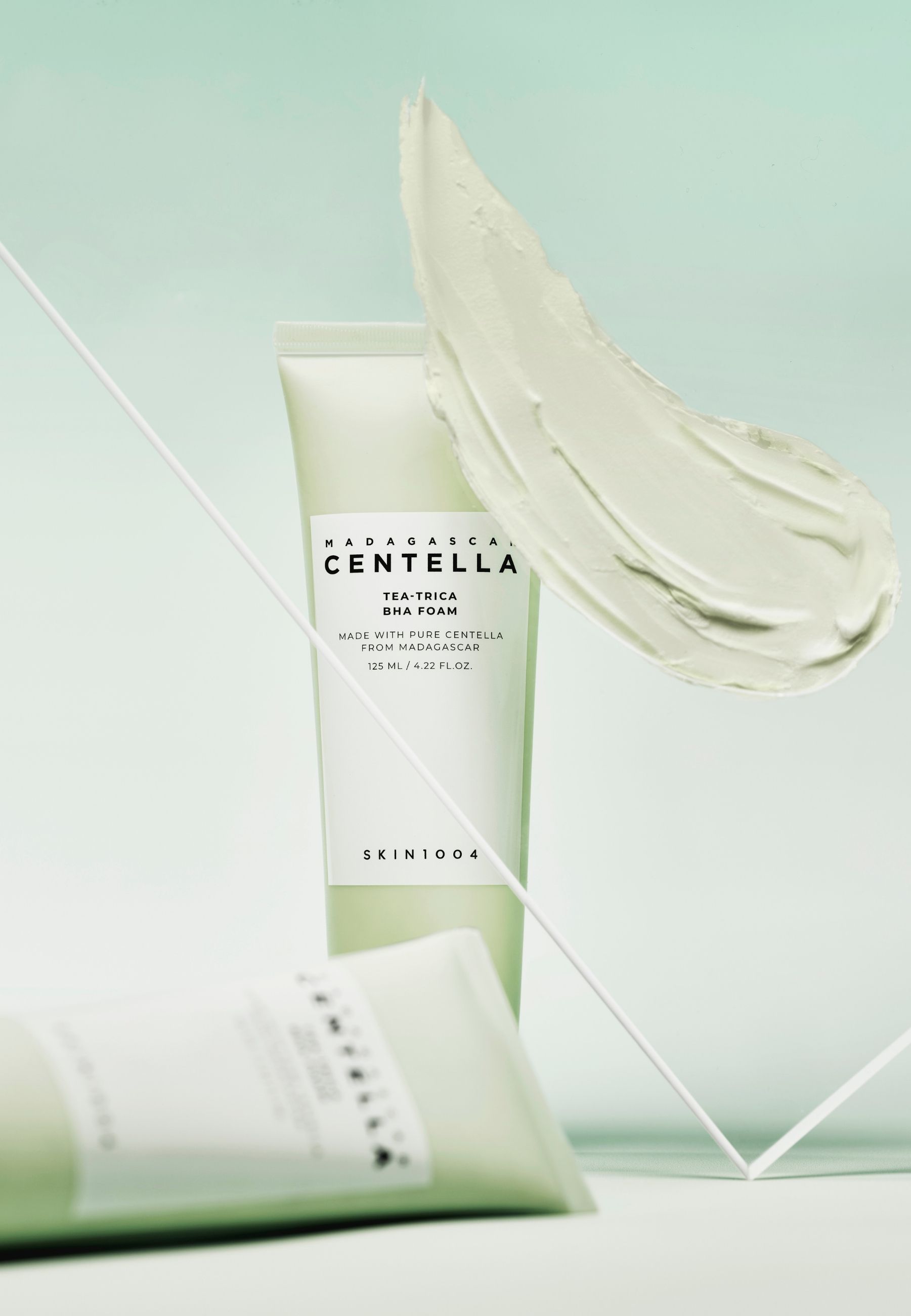 Product en crème-uitstrijkje. Tube en crème-uitstrijkje in de lucht. Witte streep. Groene achtergrond.