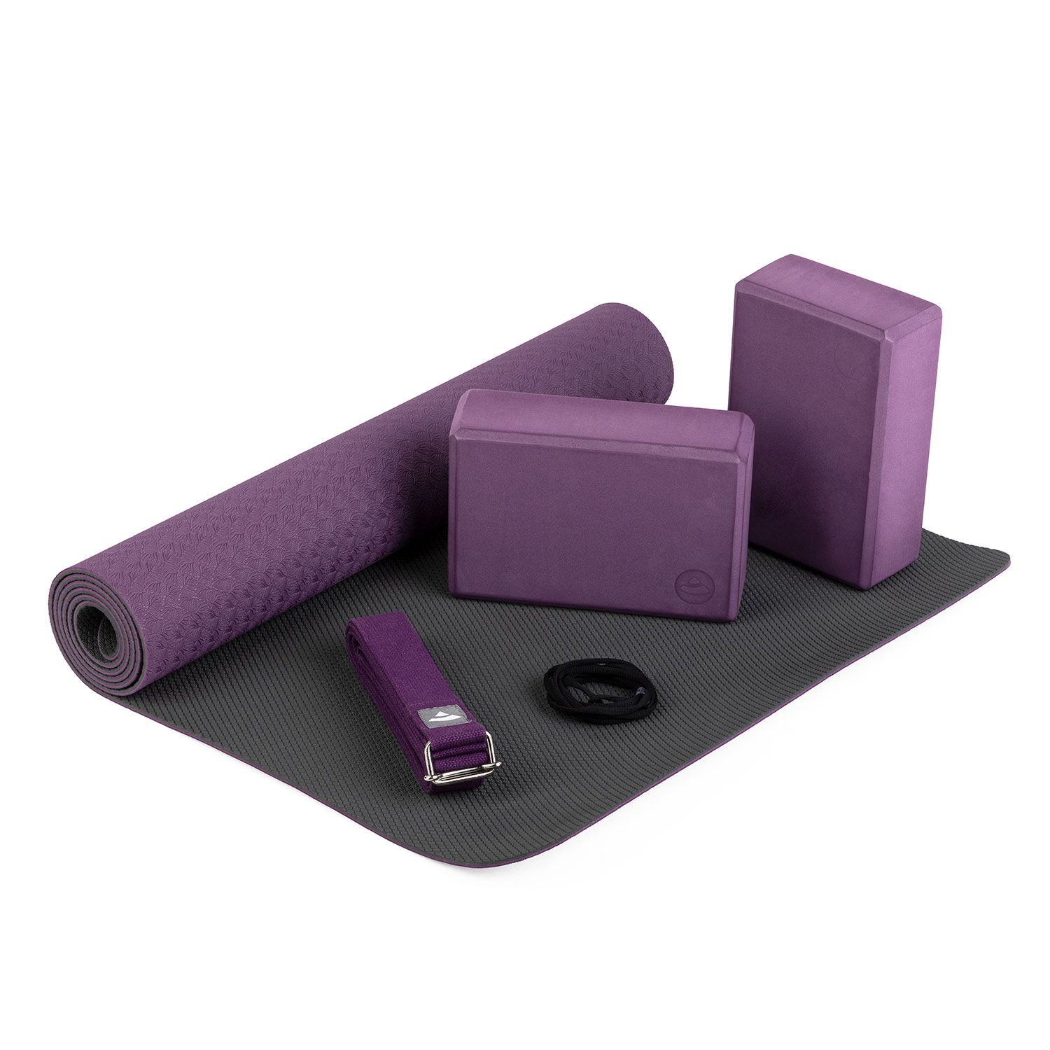Ensemble de yoga FLOW, LILA. Comprend tapis, blocs, sangle et bande. Violet et gris. Disposé sur un tapis gris.