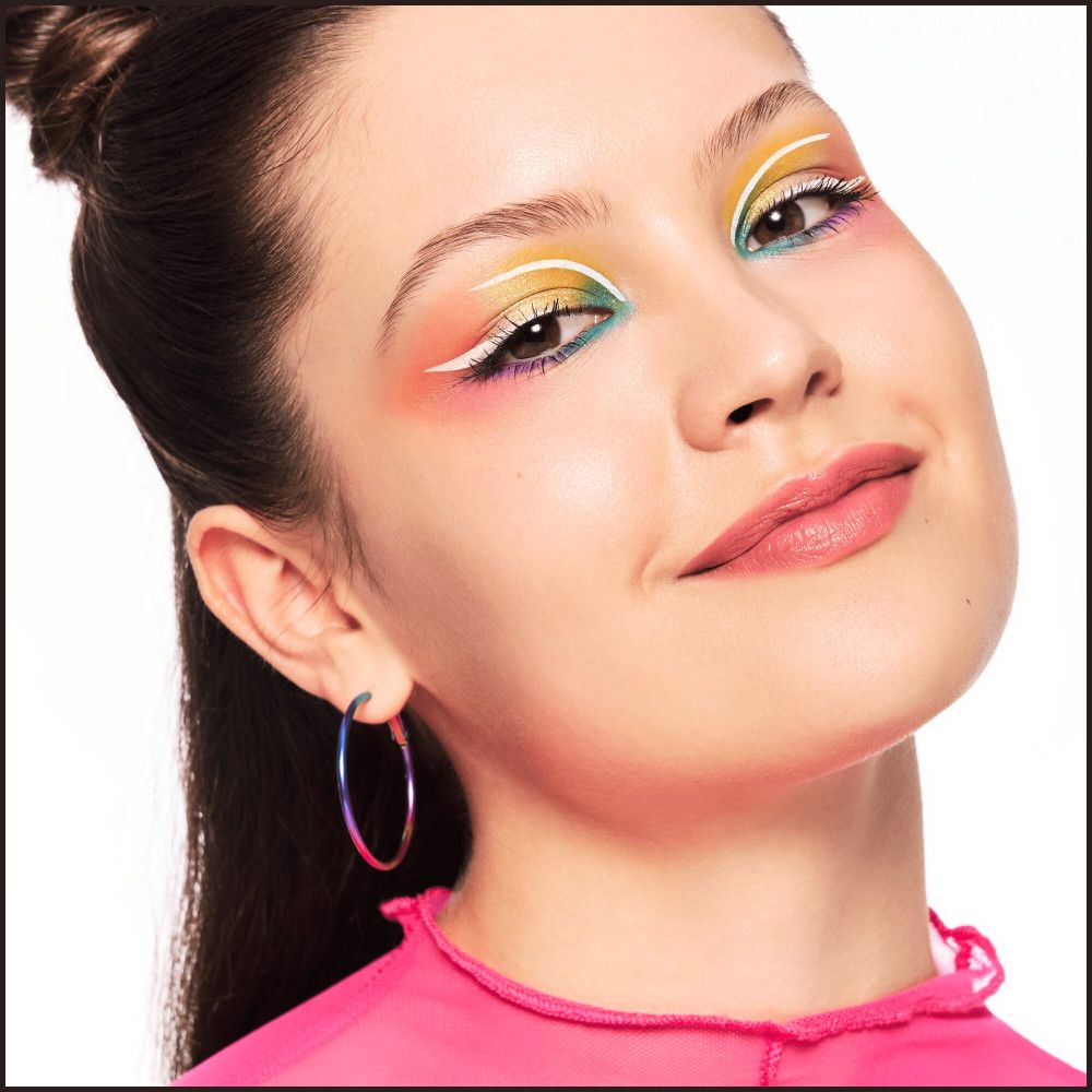 Portrait d'une femme avec maquillage des yeux coloré et boucles d'oreilles.