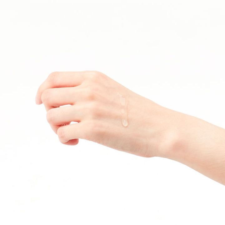 Hand met druppels heldere vloeistof. Witte achtergrond. Geen andere details.