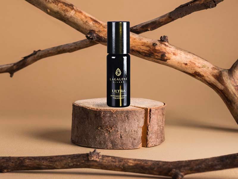 Een zwarte Lagalene Milano Ultra Intensive Care fles staat op een stuk hout, omringd door takken. Op de fles staat "ULTRA INTENSIVE TREATMENT".