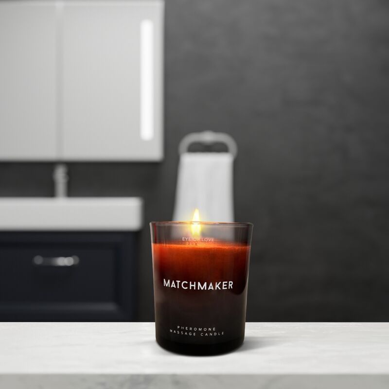 Bougie de massage 'Matchmaker' allumée dans un récipient en verre sur une table de salle de bain.