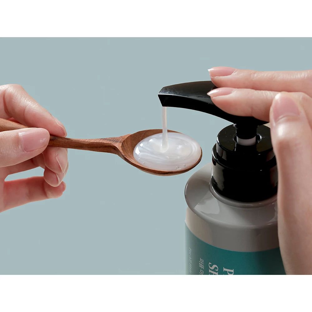 Shampoo wordt op een houten lepel gepompt. Heldere vloeistof.