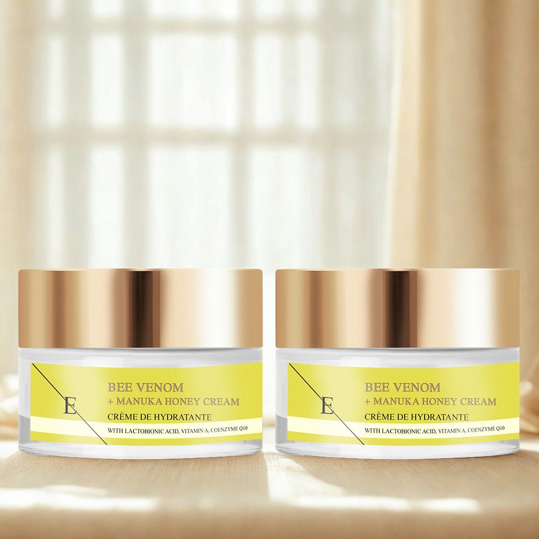 Deux pots de crème avec couvercles dorés. Étiquettes jaunes avec texte: Bee Venom + Manuka Honey Cream. Sur fond clair.