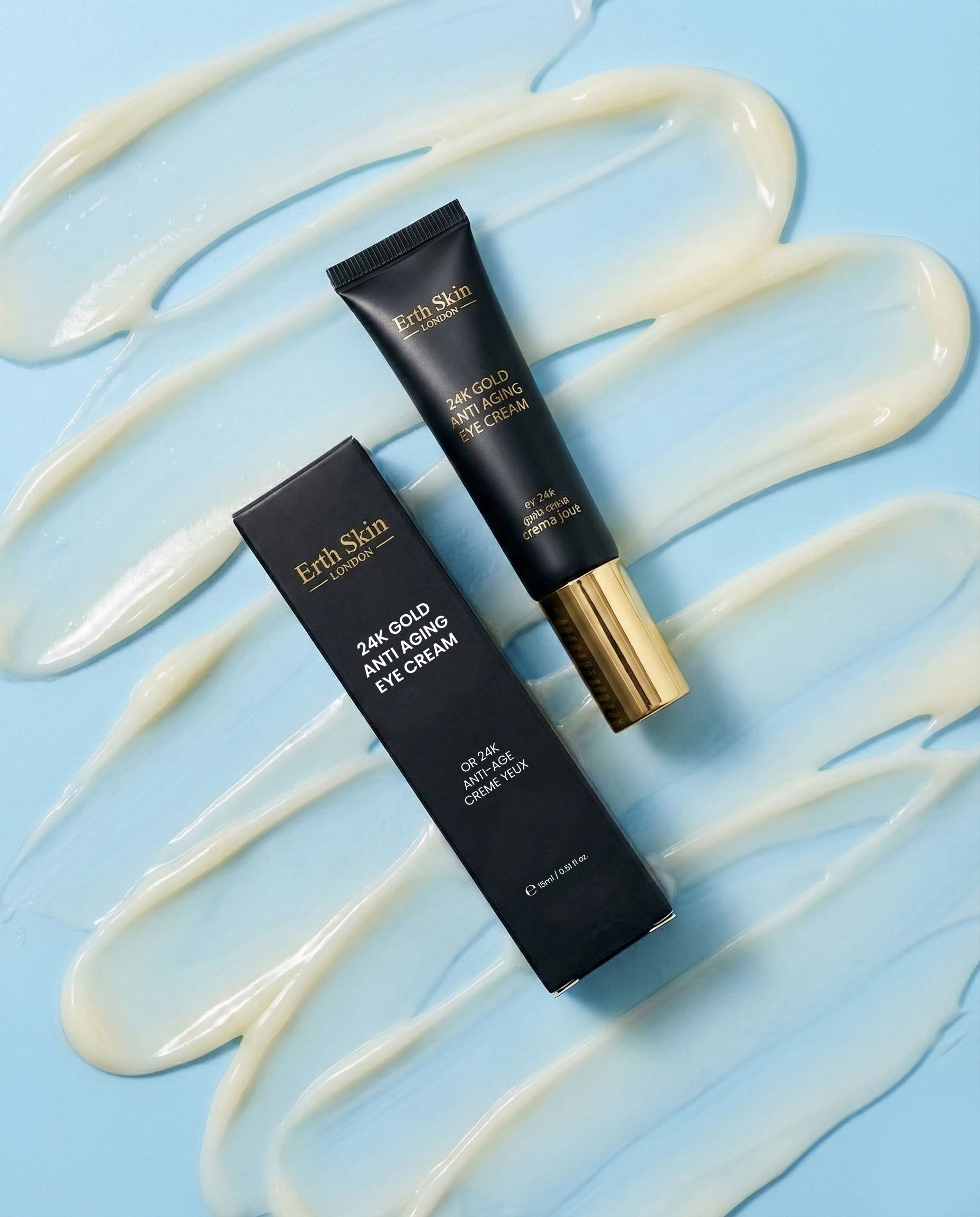 Tube et boîte pliante ErthSkin London Crème contour des yeux 24k Gold, entourés de traînées de crème.