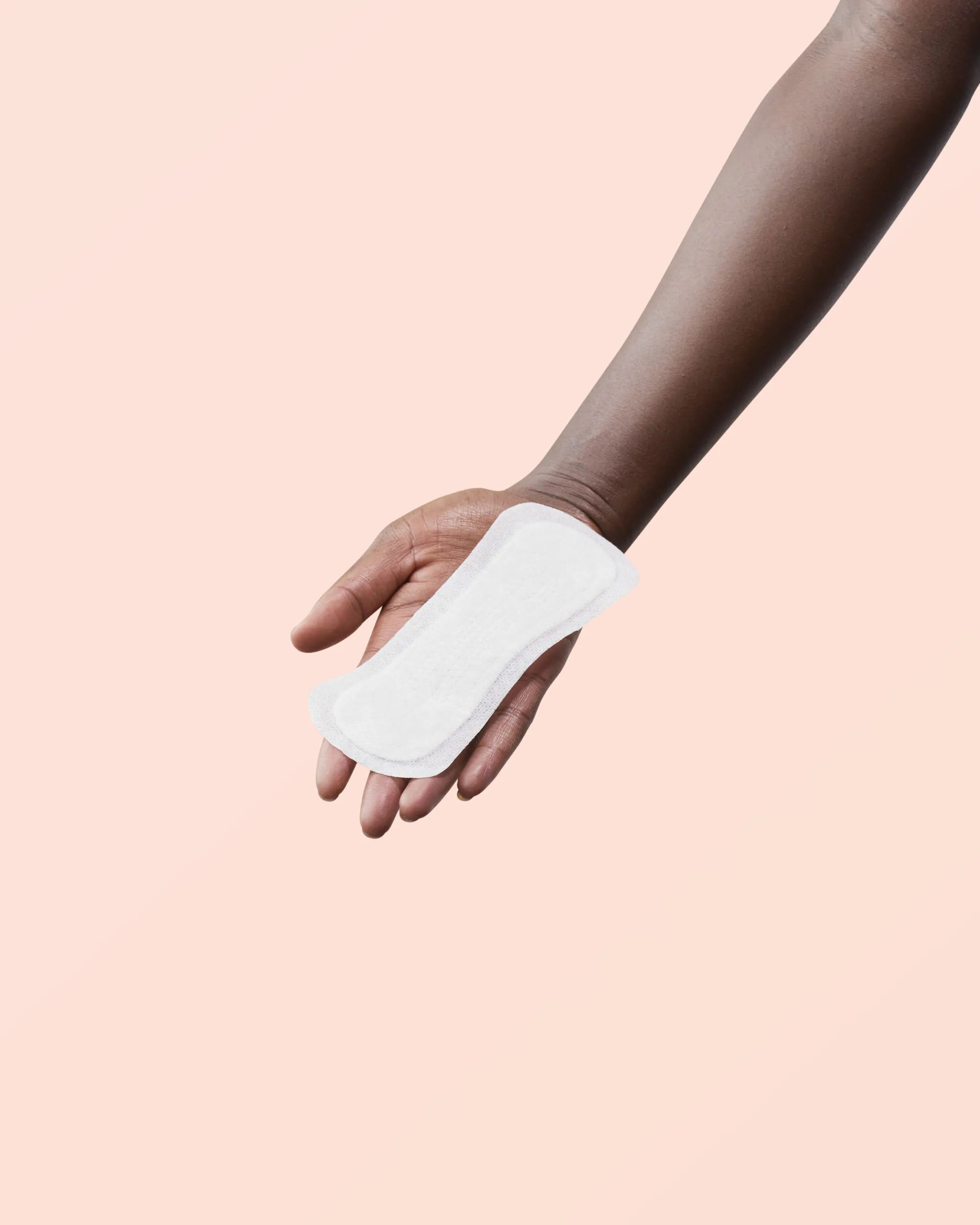 Serviette hygiénique blanche dans une main. Sur fond rose. Coton. Normal.