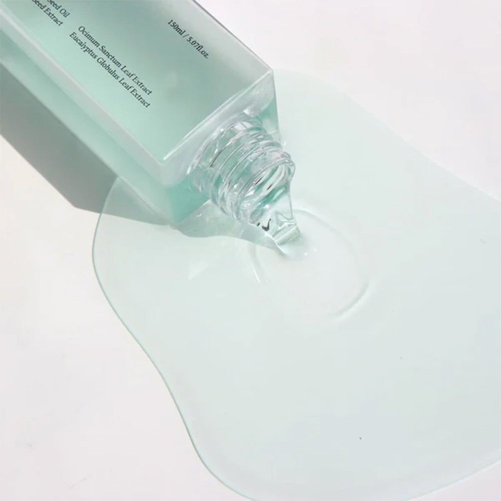 Close-up van Dr. Althea Gentle Pore Vegan Cleansing Oil die uit een fles op een oppervlak wordt gegoten.