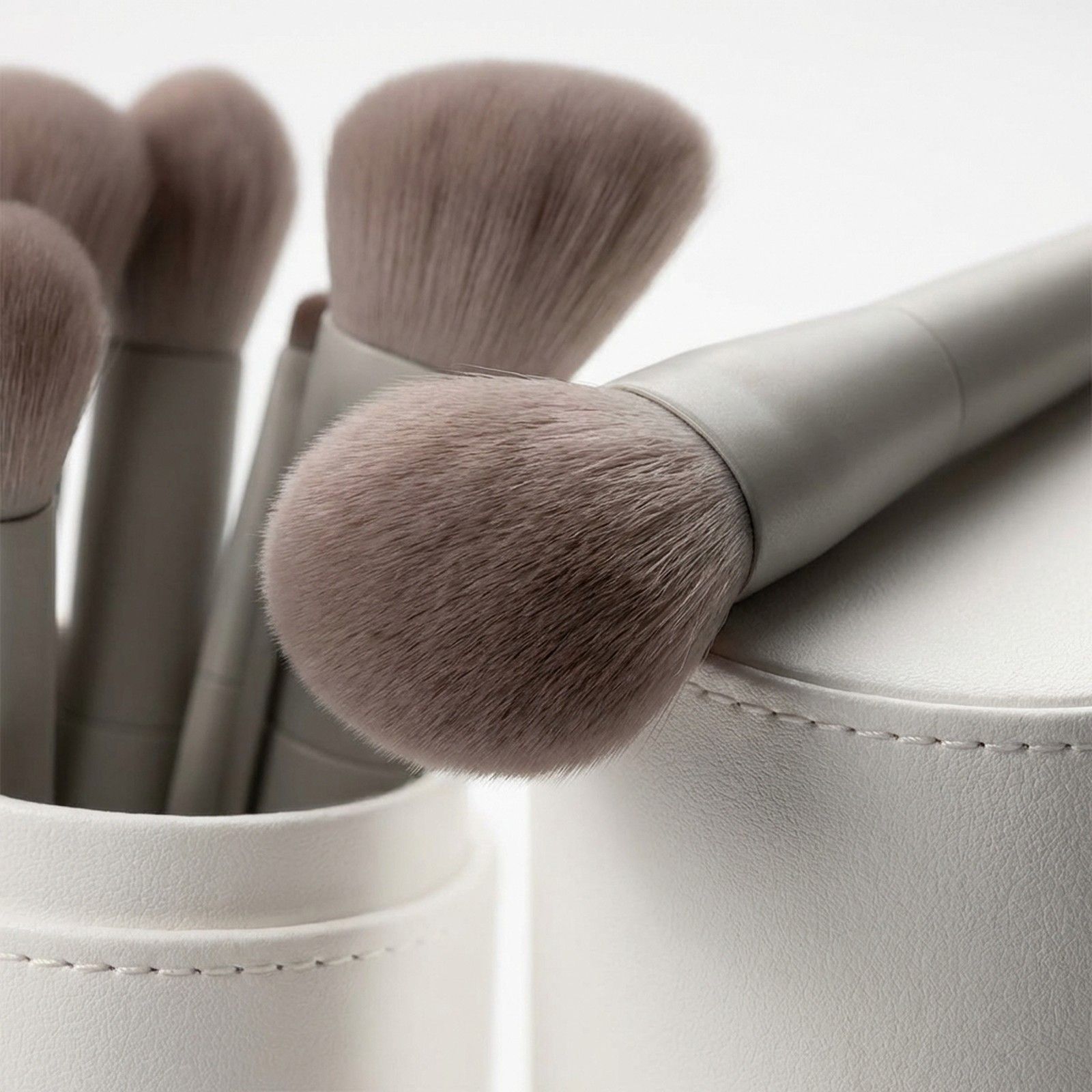 Ensemble de pinceaux de maquillage gris à poils doux dans un support blanc.