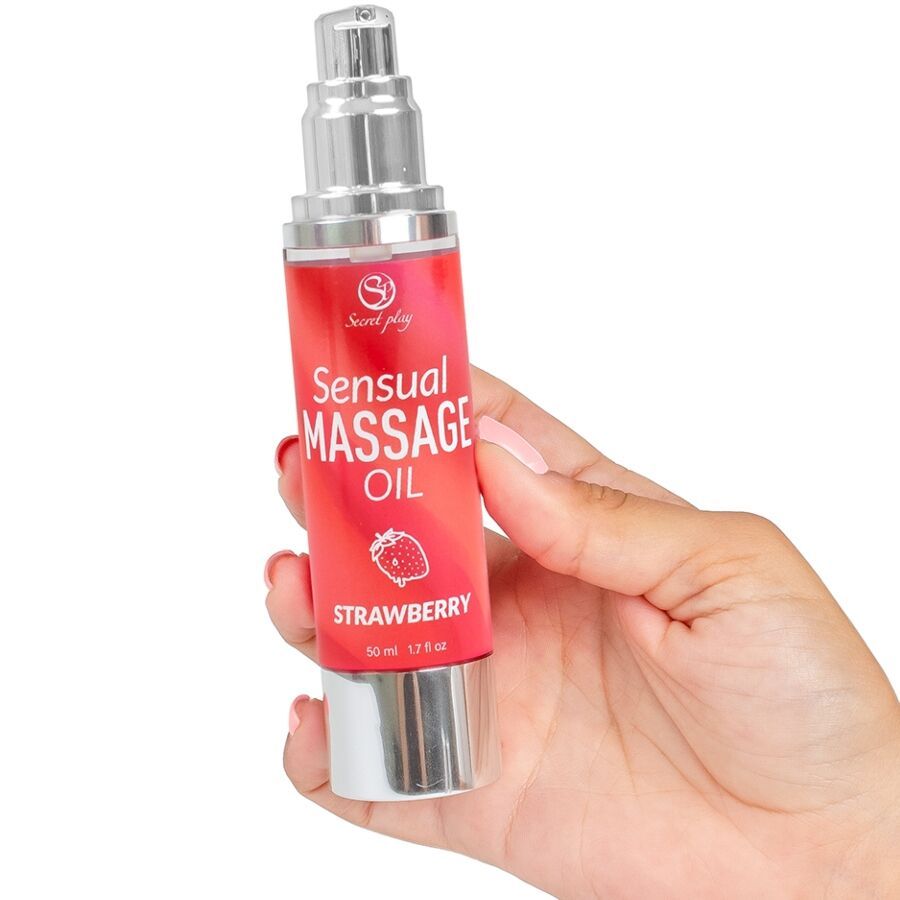 Rode fles met zilveren pomp. Opschrift: Sensual Massage Oil Strawberry. Hand houdt de fles vast.
