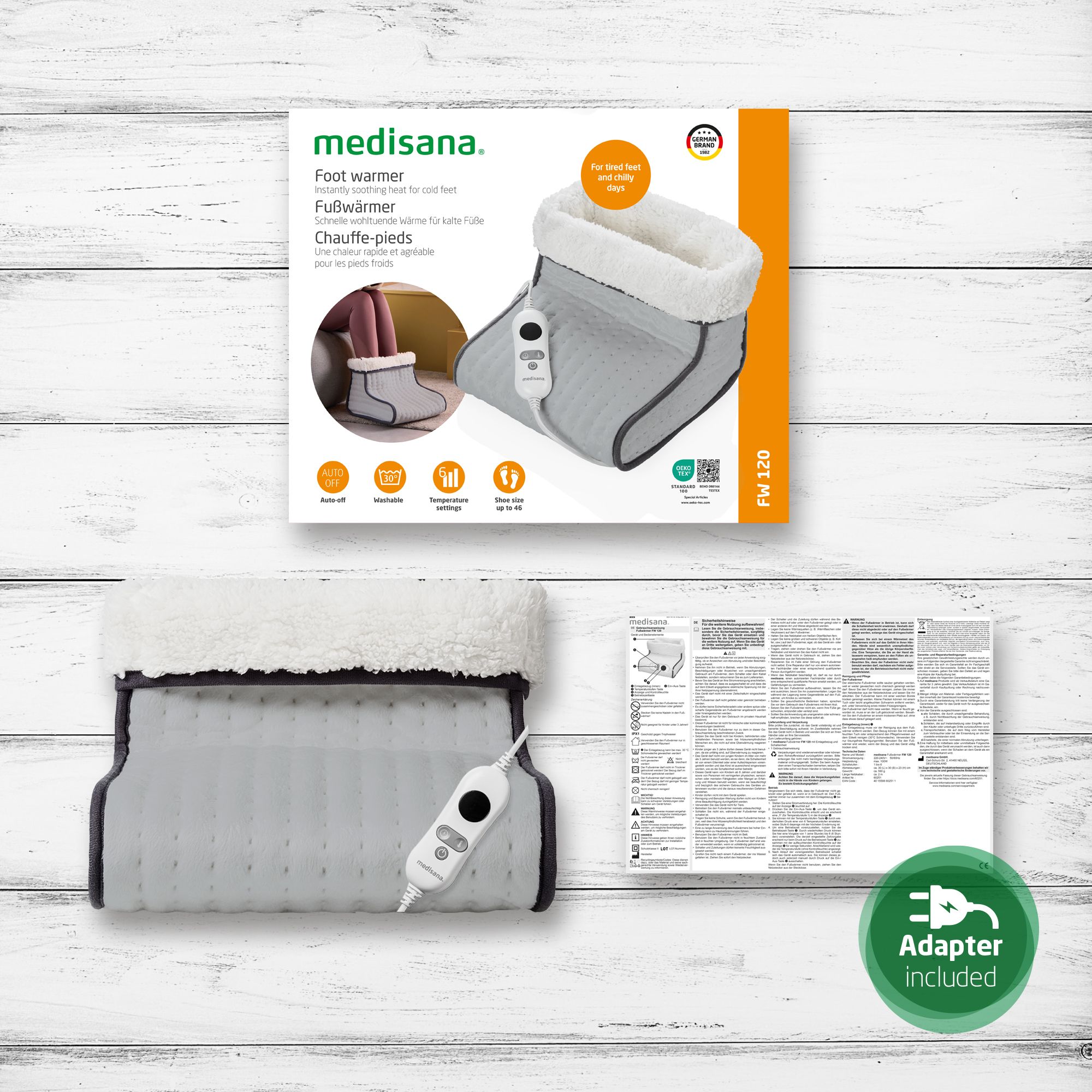 Emballage du produit avec chauffe-pieds, panneau de commande et accessoires. Texte : Adaptateur inclus, FW 120. Le produit est gris avec une doublure intérieure blanche.