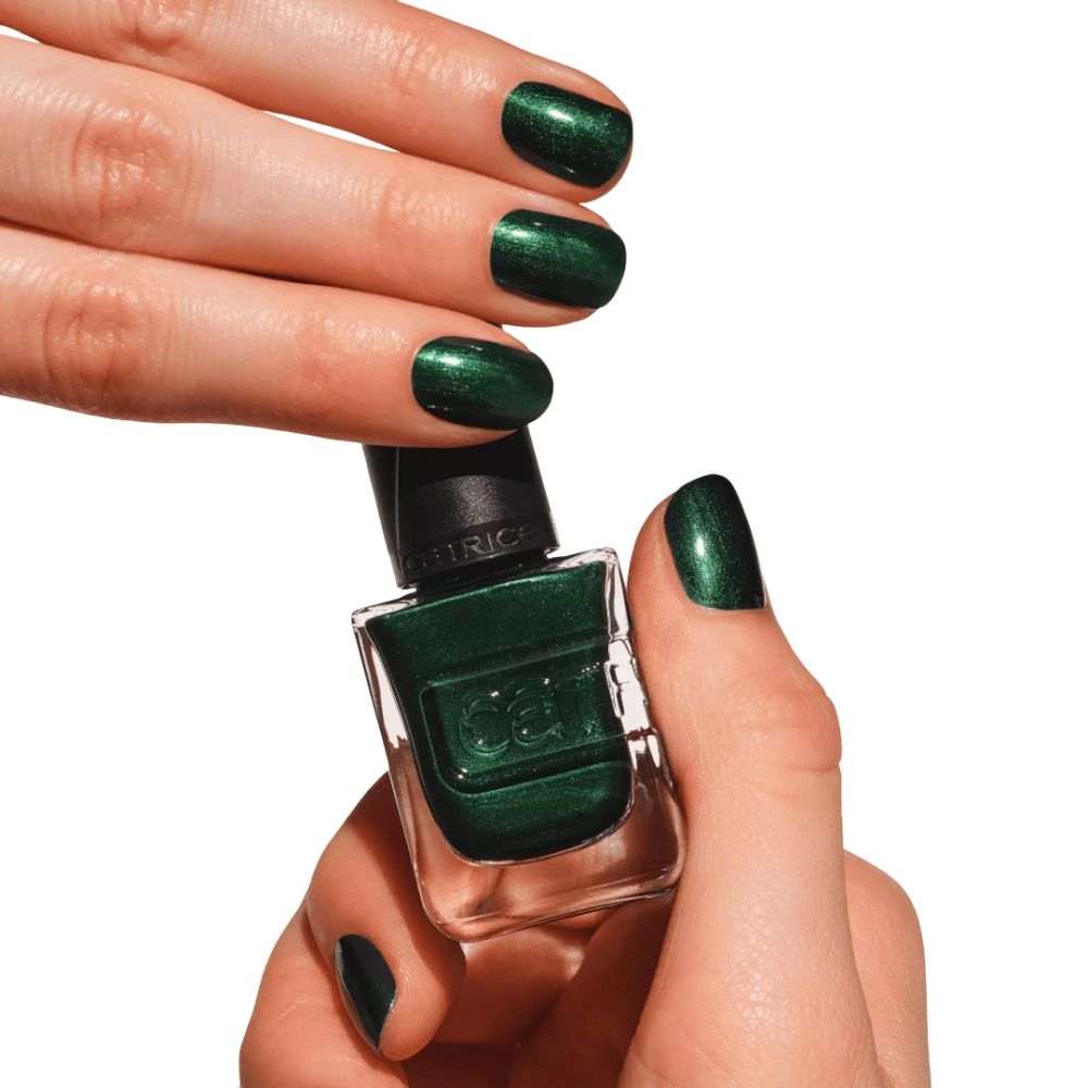 Mains avec ongles vernis en vert tenant un flacon de vernis. Marque Catrice visible. Flacon et ongles verts.