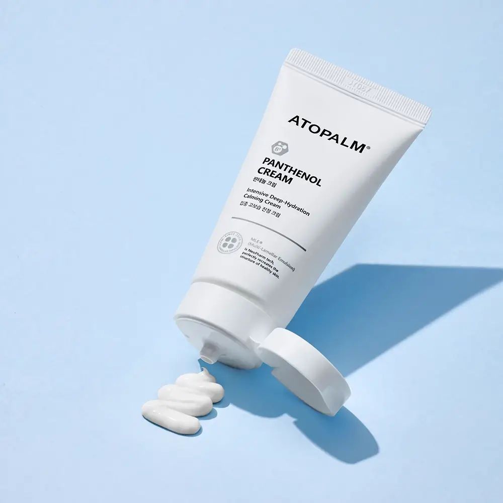 Tube blanc avec logo et nom du produit, avec bouchon ouvert et produit. Inscription : ATOPALM, Panthenol Cream.