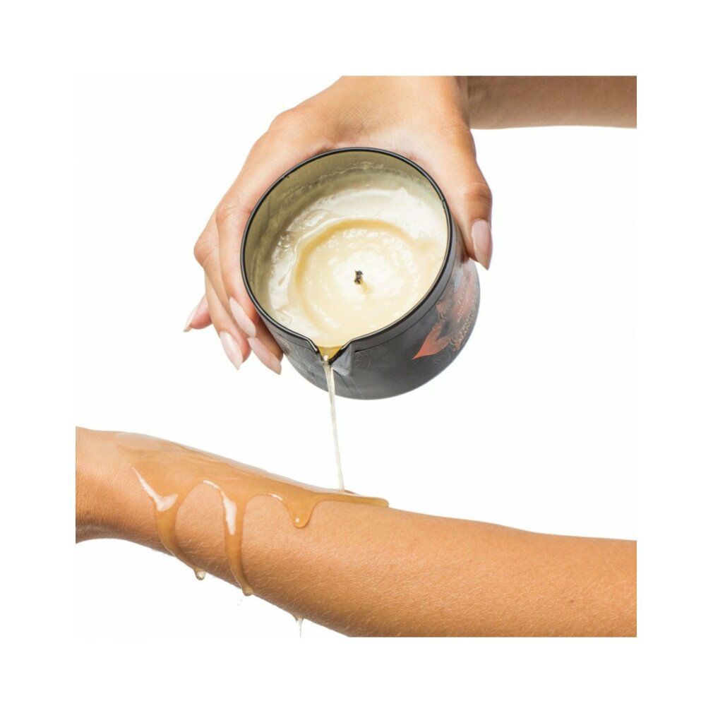 Persoon giet gesmolten was uit een massagekaars op een arm. Kaars en arm zichtbaar.