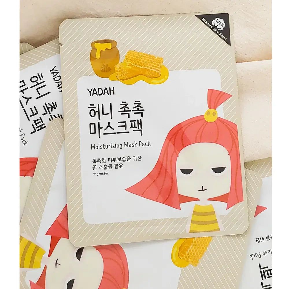 Plusieurs masques faciaux YADAH. Emballage avec illustration de miel et texte coréen. Inscription : Moisturizing Mask Pack.