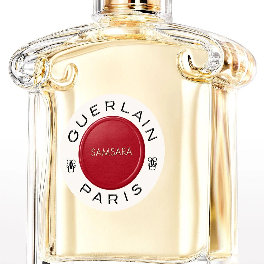 Parfumfles met rood etiket. Opschrift: GUERLAIN PARIS, SAMSARA. Transparante glazen fles met gouden dop.