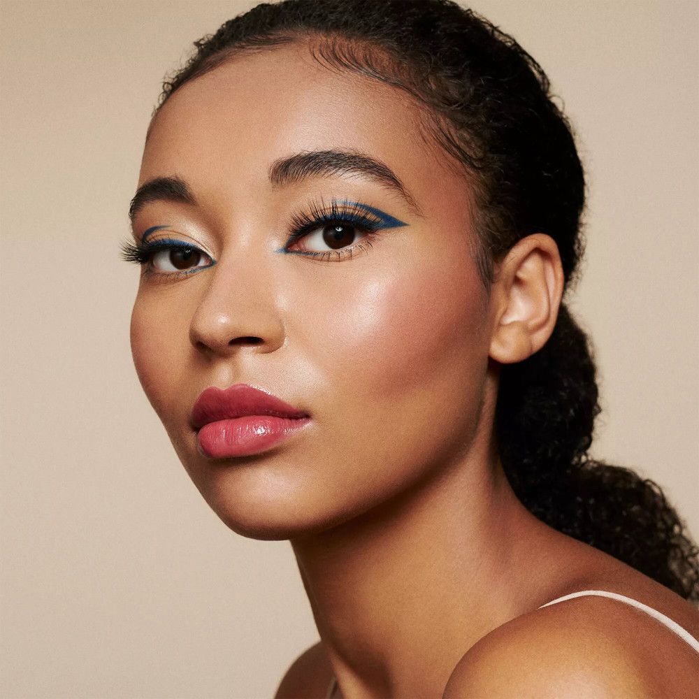 Close-up van een gezicht met blauwe eyeliner en valse wimpers. Donkere huid, donker haar.