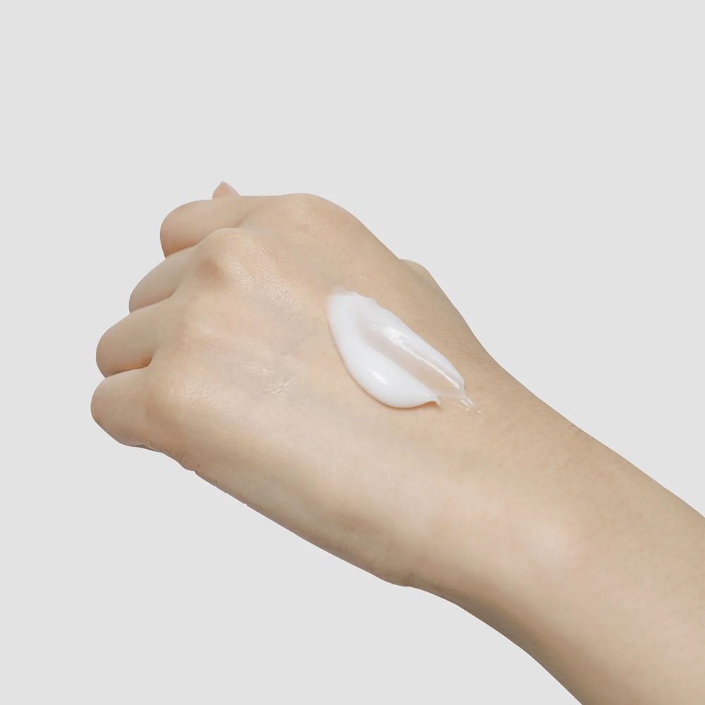 Main avec crème blanche. La crème est appliquée sur le dos de la main.