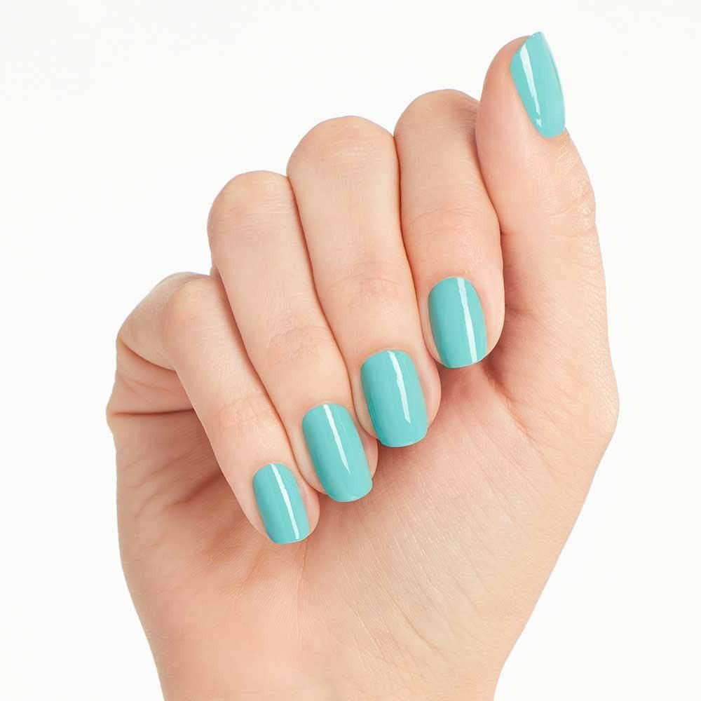 Main avec ongles peints en turquoise. Les ongles sont courts et uniformément vernis.