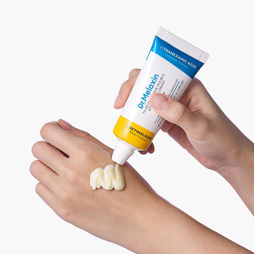Een hand drukt een dubbele oogcrème uit, een witte en een gele crème worden op de andere hand aangebracht.