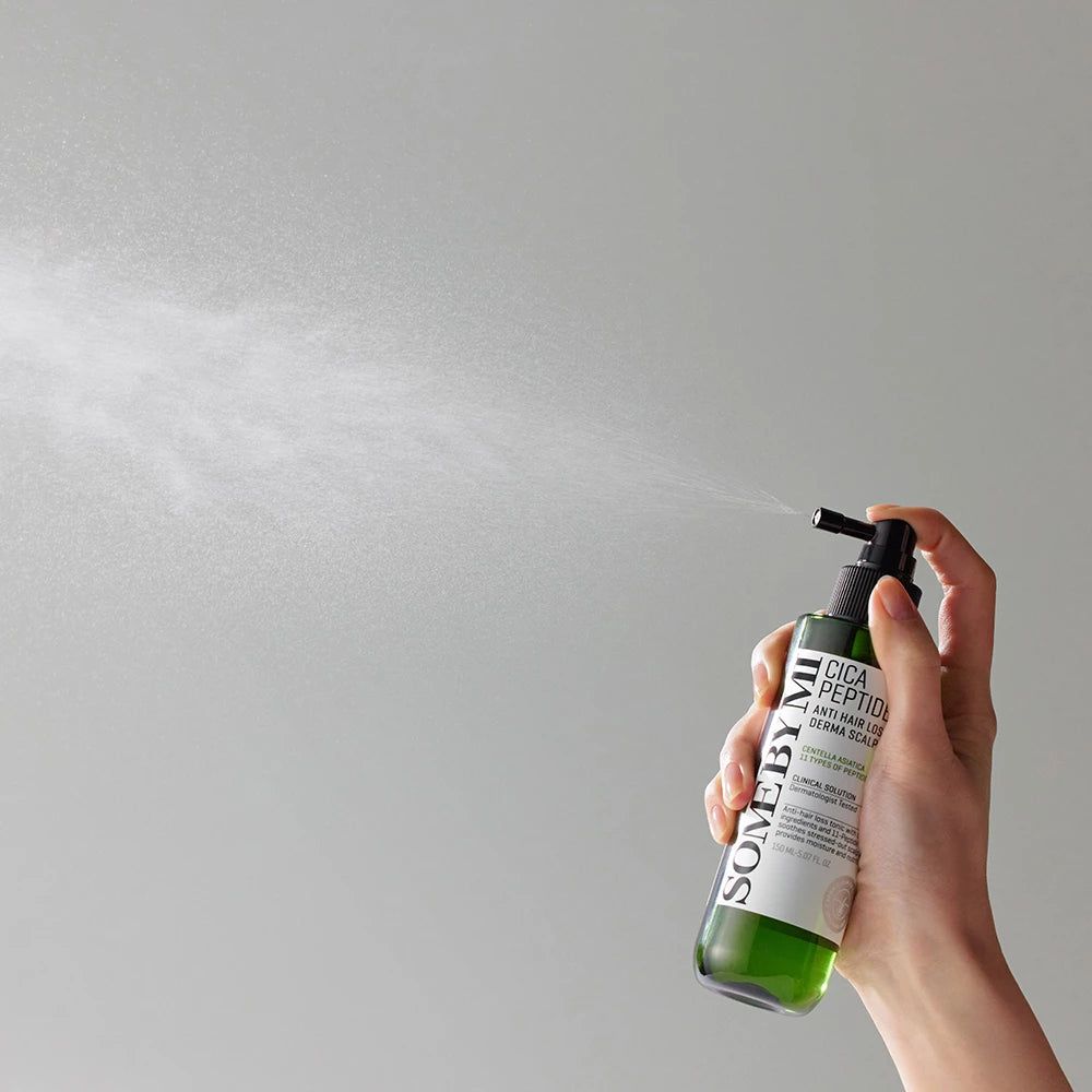Hand houdt groene fles met zwarte spraykop vast. Opschrift: Cica Peptide Anti Hair Loss Derma Scalp Tonic. Merk: SOME BY MI. Sproeimist.