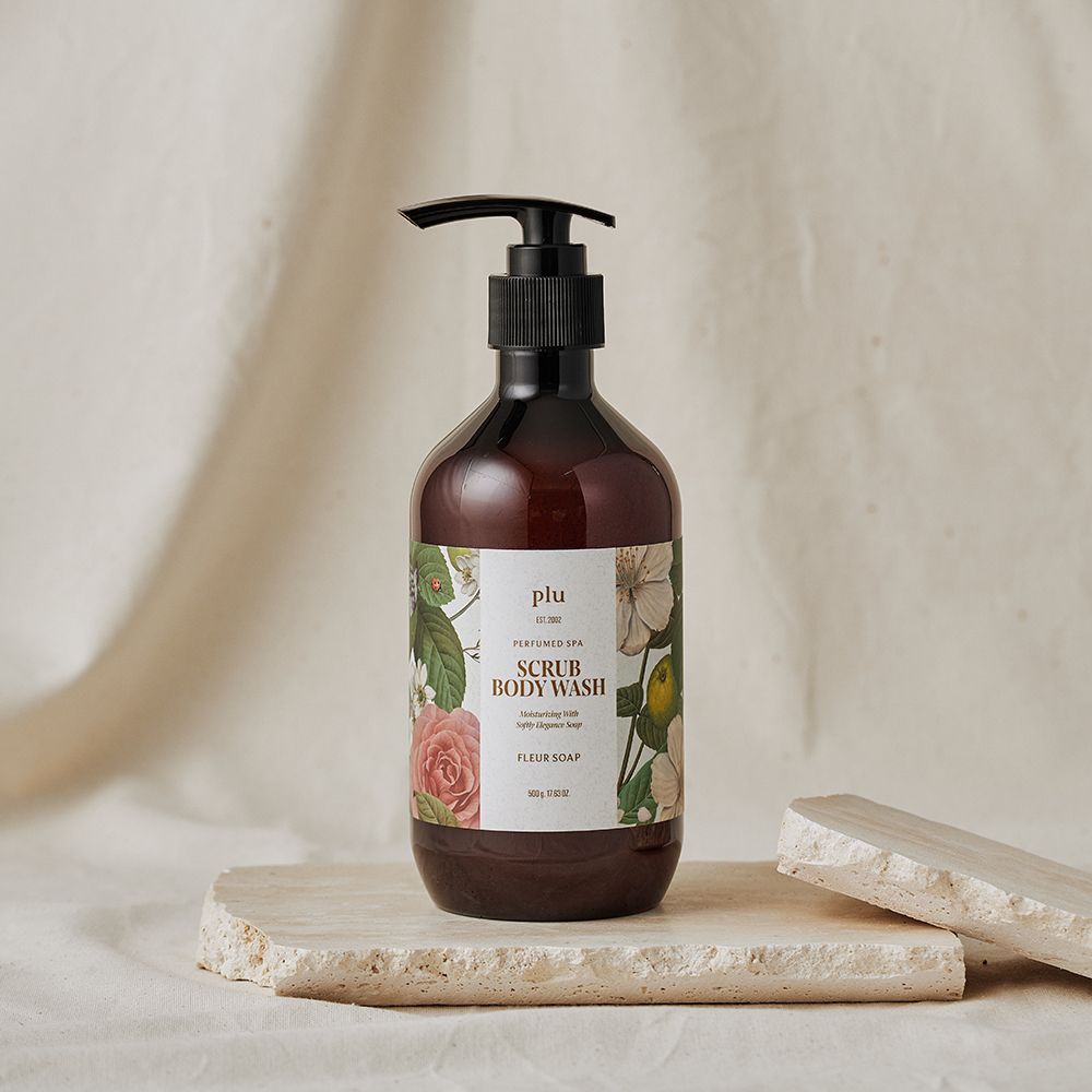 Flacon marron avec pompe noire. Étiquette florale et texte. Posé sur une pierre.