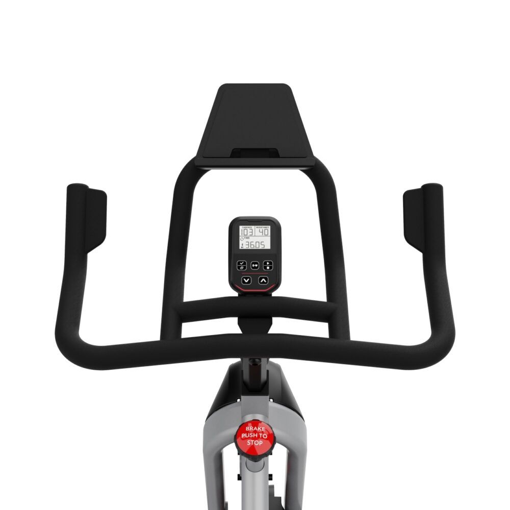 Gros plan sur le guidon d'un vélo d'intérieur. Visible : écran, poignées, bouton d'arrêt d'urgence. Couleur noire.