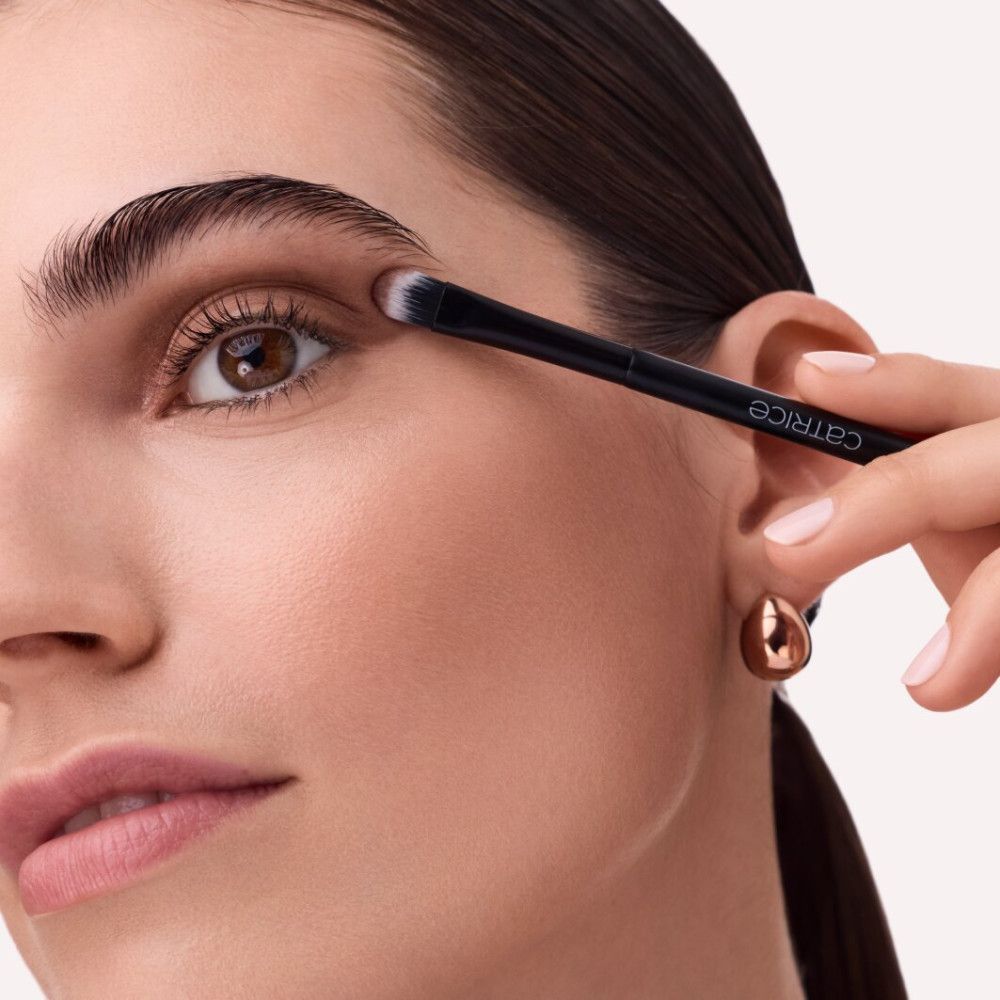 Vrouw gebruikt een zwarte oogschaduwkwast. Merk Catrice.