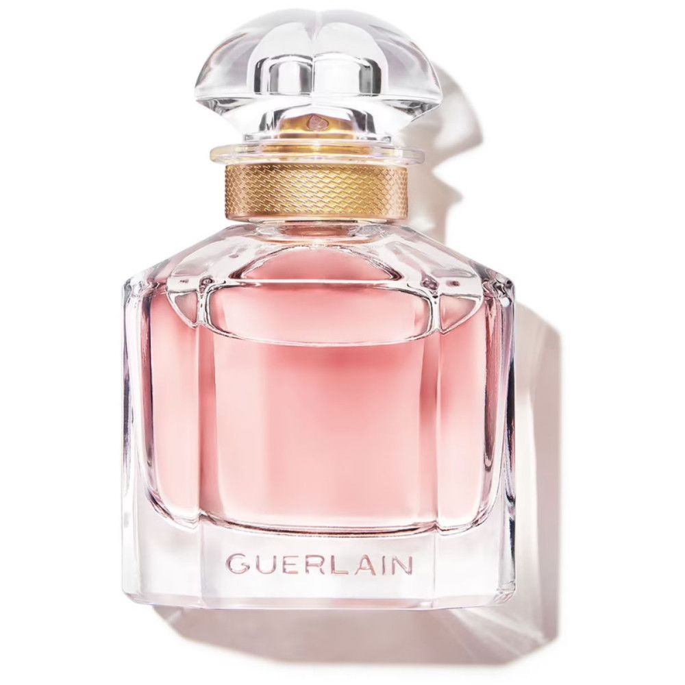 Flacon de parfum carré avec liquide rose, bouchon doré et couvercle transparent. Forme géométrique.