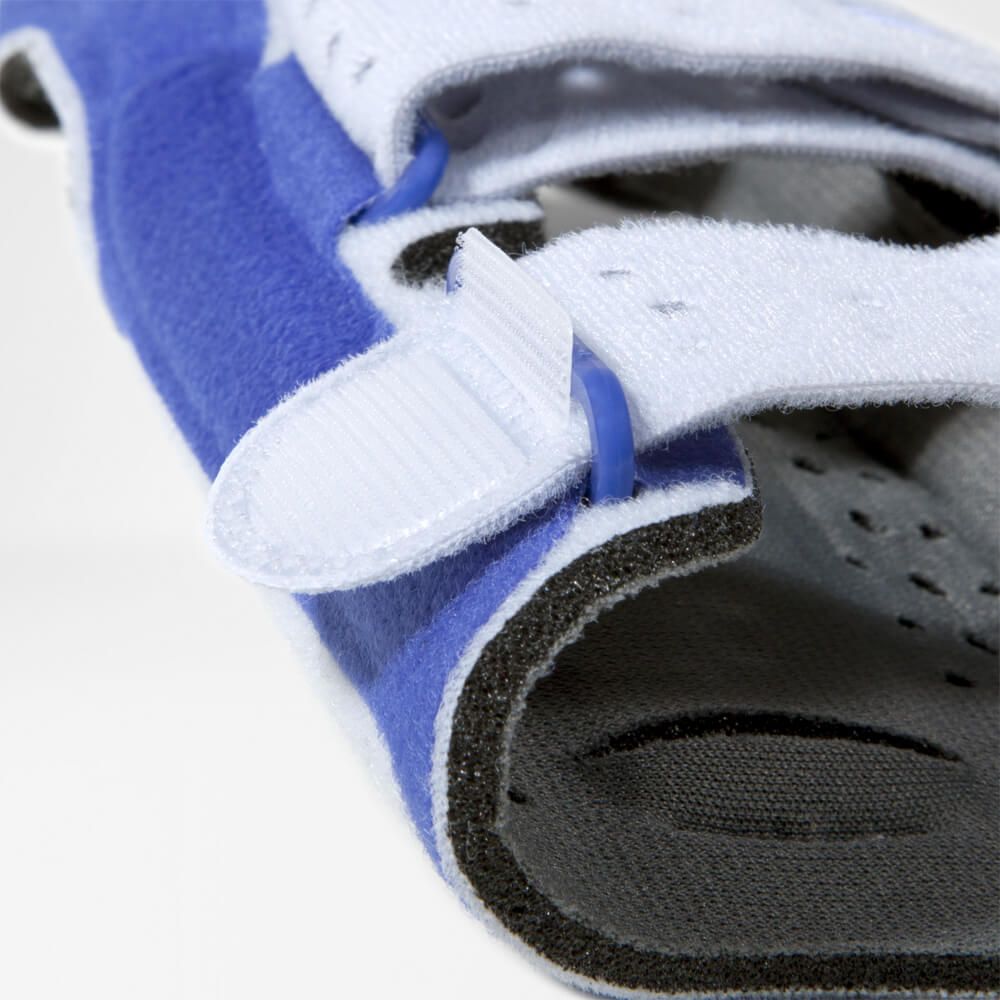 Detailopname van de polsbrace. Blauwe en witte materialen, klittenbandsluiting en blauwe plastic ringen.