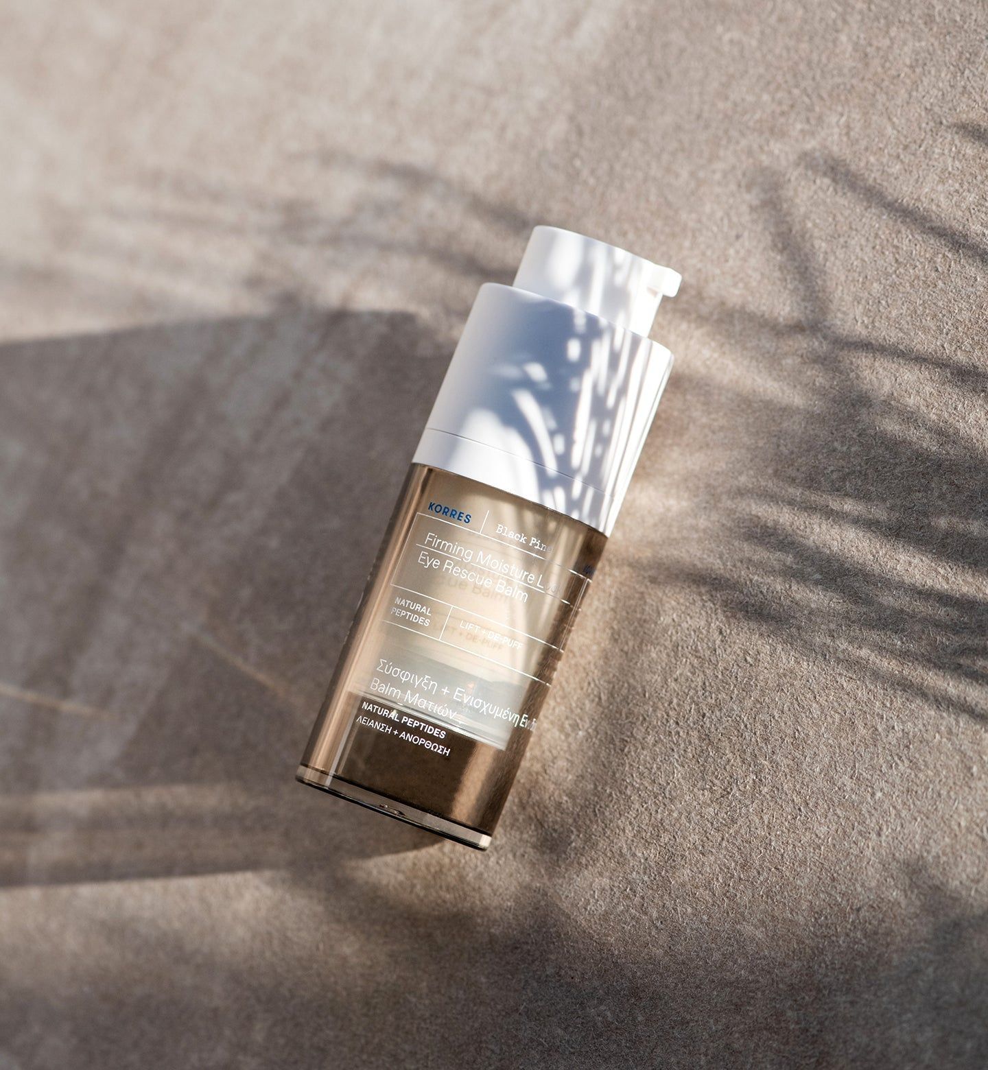 Fles met pomp. Merk KORRES, productnaam op etiket. Op zandkleurige ondergrond.