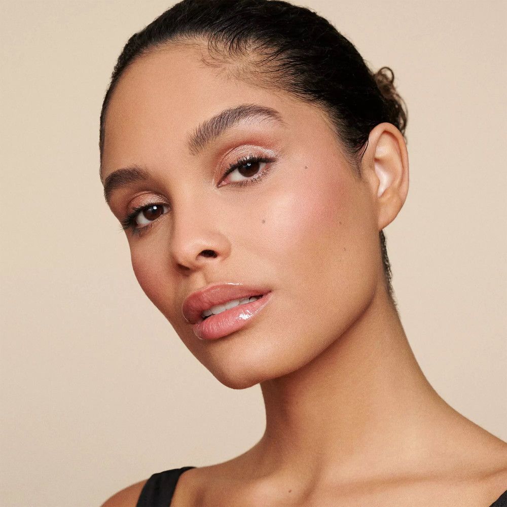 Portrait d'une femme avec maquillage léger. Peau bronzée, joues roses, lèvres brillantes.