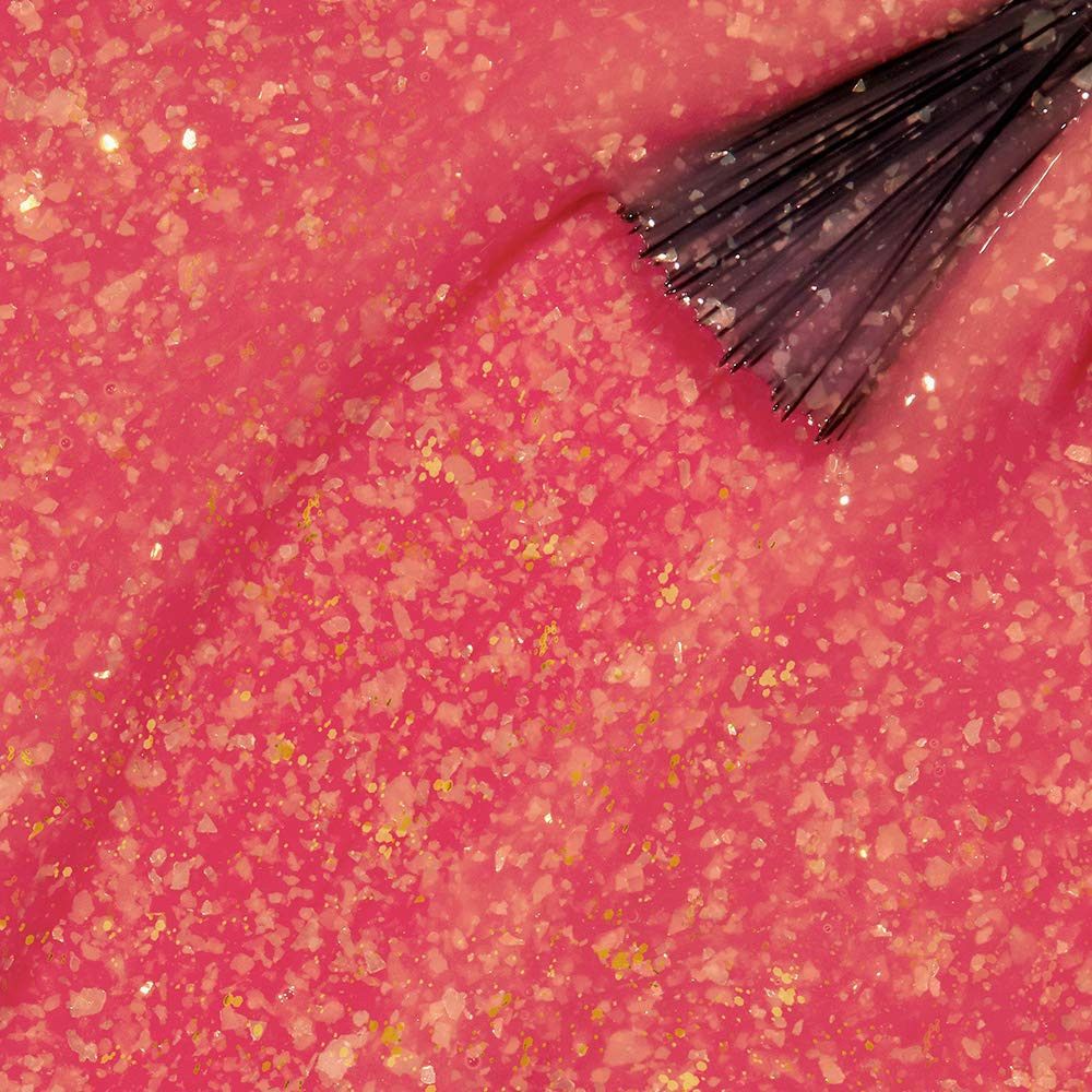 Roze nagellak met gouden glitter, aangebracht met een borstel. Close-up.