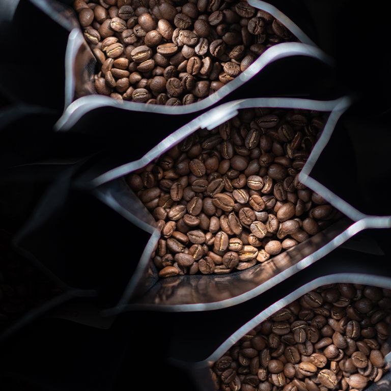 Close-up van drie geopende zakken met koffiebonen. Koffiebonen zijn zichtbaar.