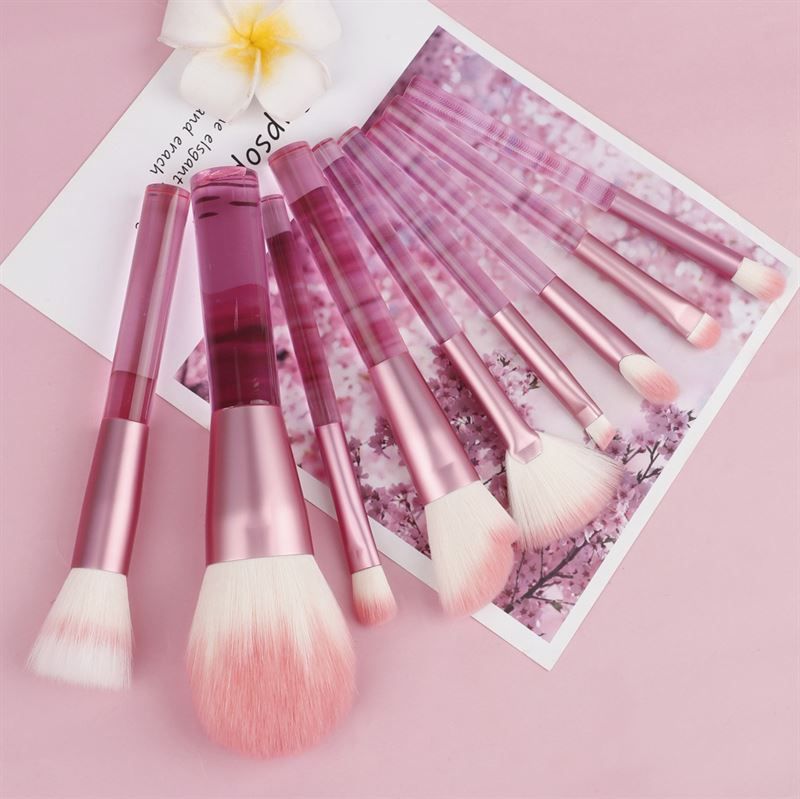 Ensemble de pinceaux de maquillage roses. Plusieurs pinceaux avec manches transparents et poils roses. Sur fond rose.