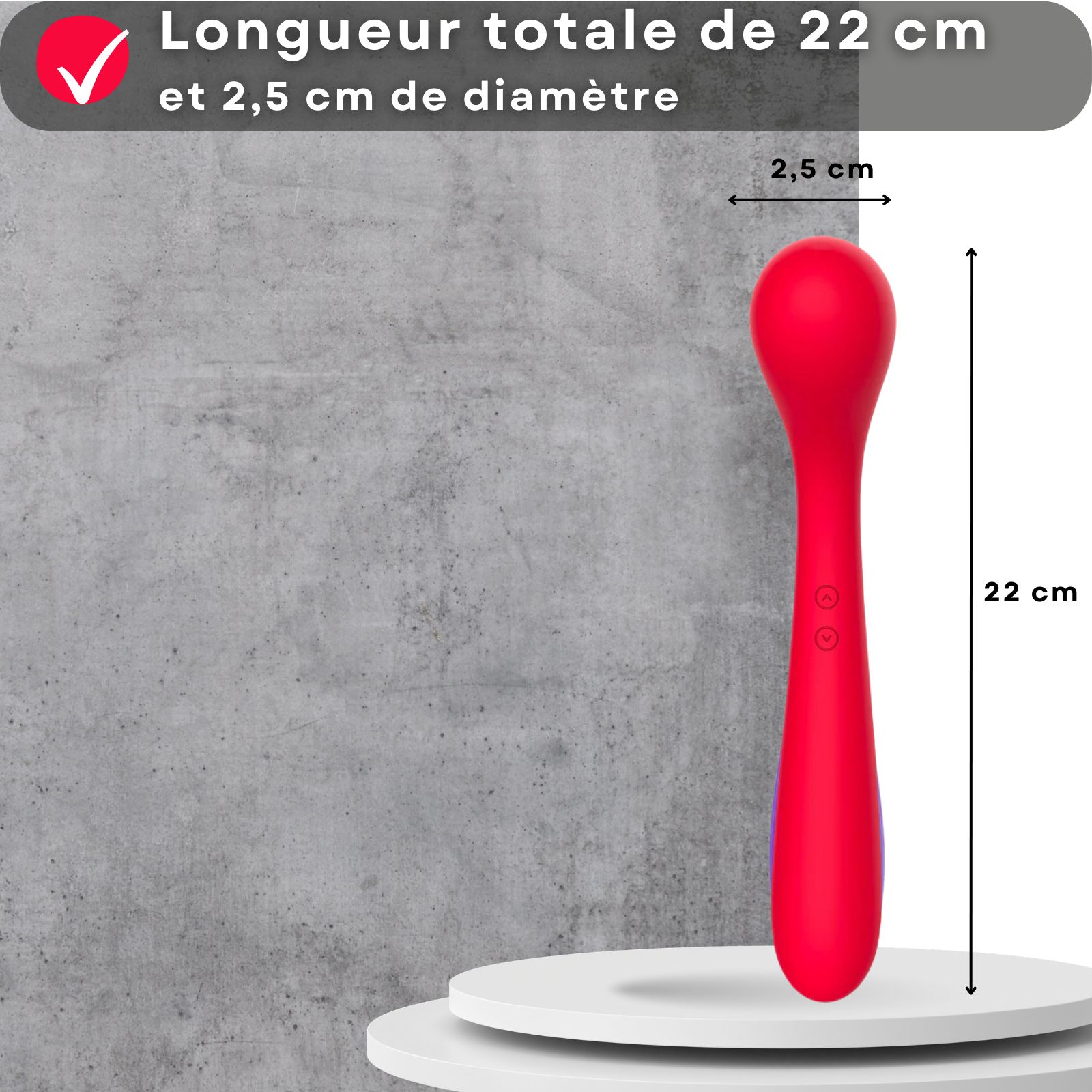 Vibrateur rouge avec mesures. 22 cm de long, 2,5 cm de diamètre. Sur socle devant mur.