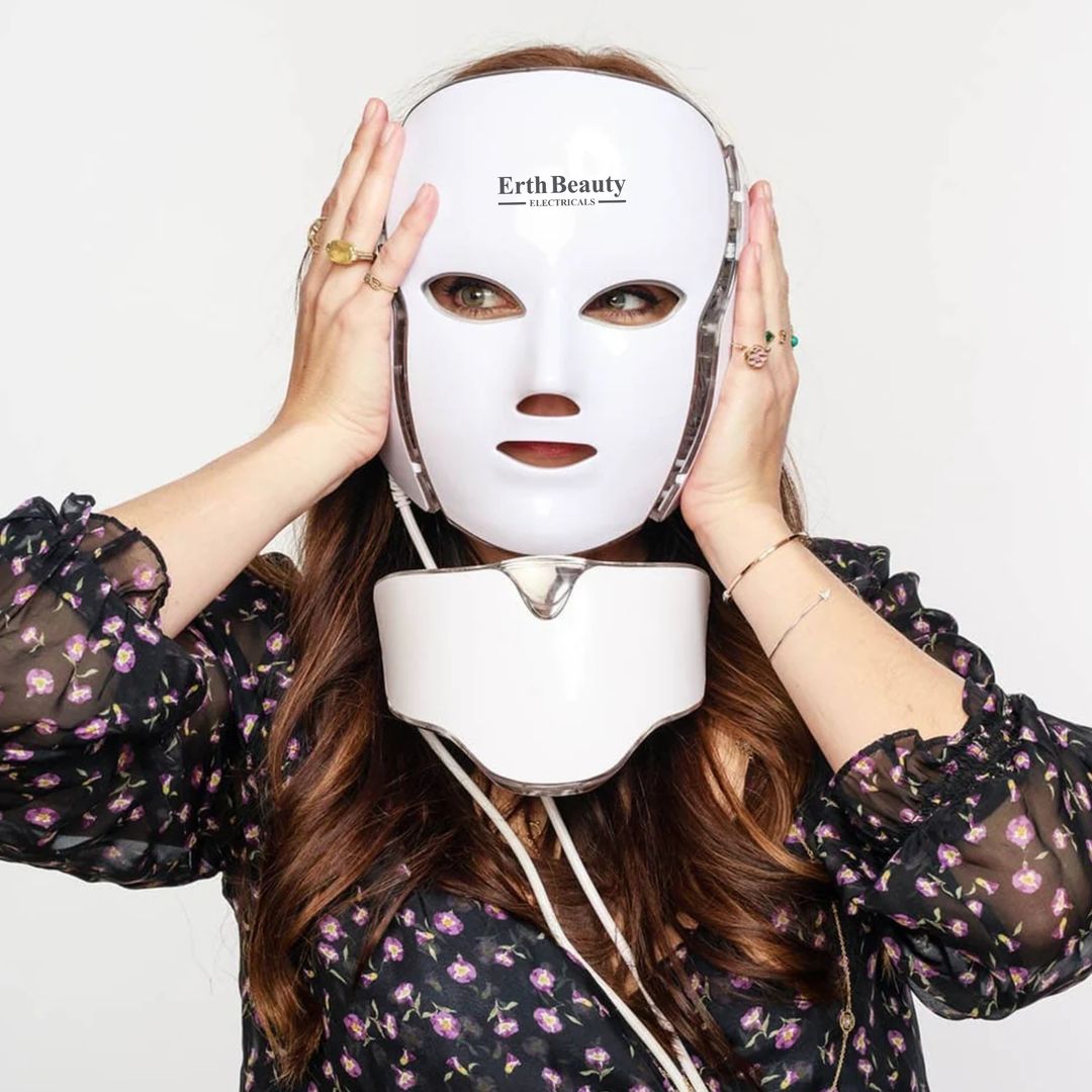 Een vrouw draagt een wit LED-gezichtsmasker. Op het masker staat "Erth Beauty". Ze raakt het masker aan met haar handen.