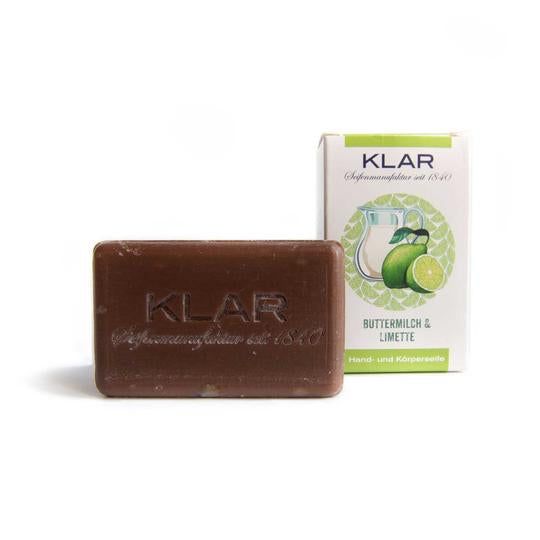 Savon brun avec logo Klar en relief. Forme rectangulaire. Emballage avec illustration du produit. Texte : Babeurre & Citron vert, Savon mains et corps.